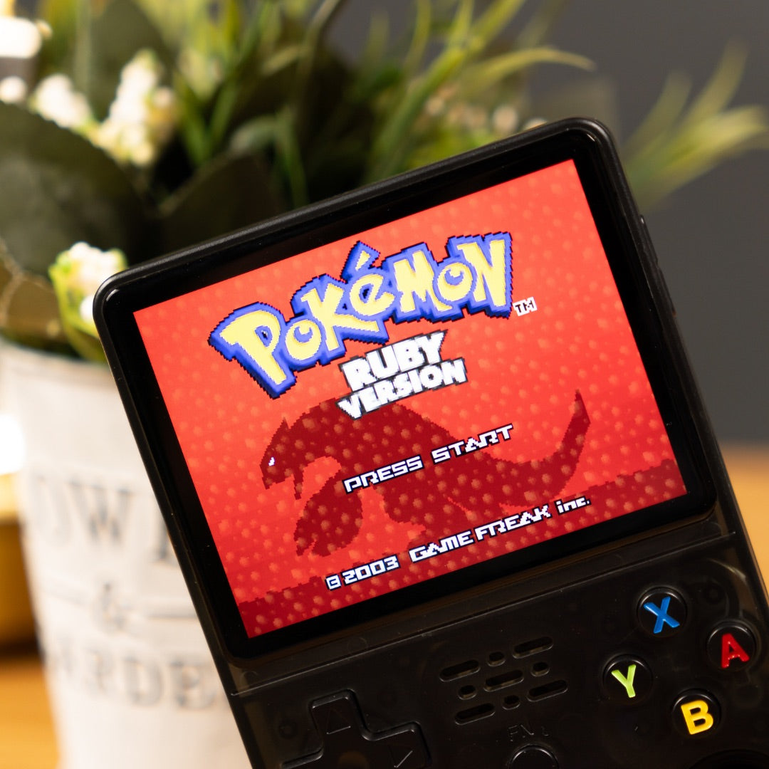 Vintage handheld gaming console displaying 'Pokémon Ruby Version' on a blurred plant background